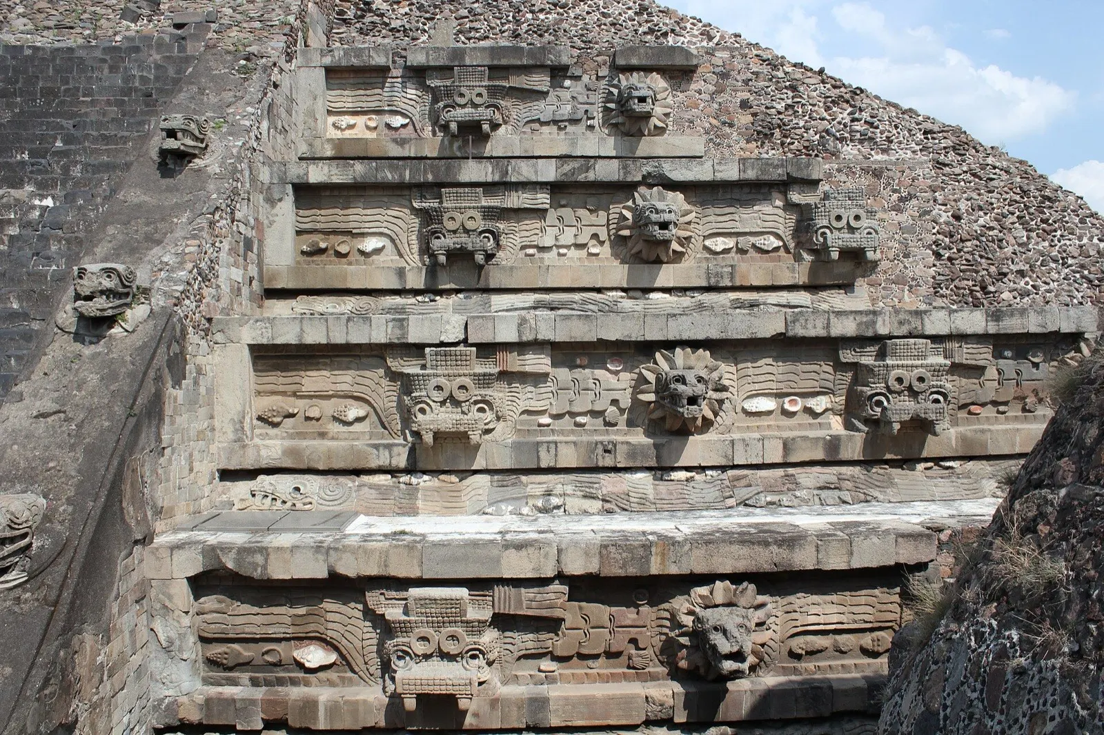 Detalle del Templo de la Serpiente Emplumada en Teotihuacán con relieves de serpiente y jaguar en piedra.